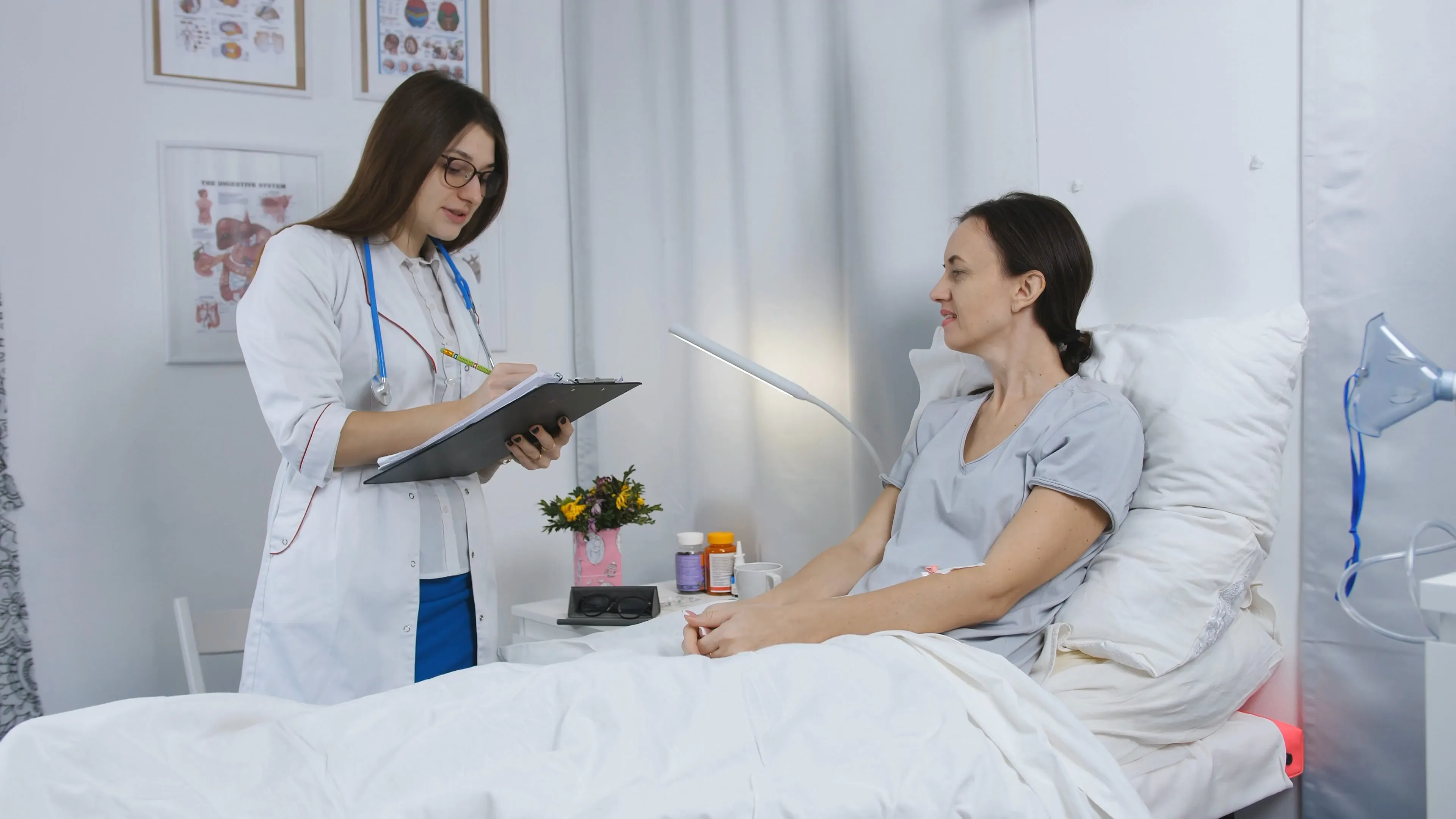 Doctor taking notes at the bedside of a patient on a ward