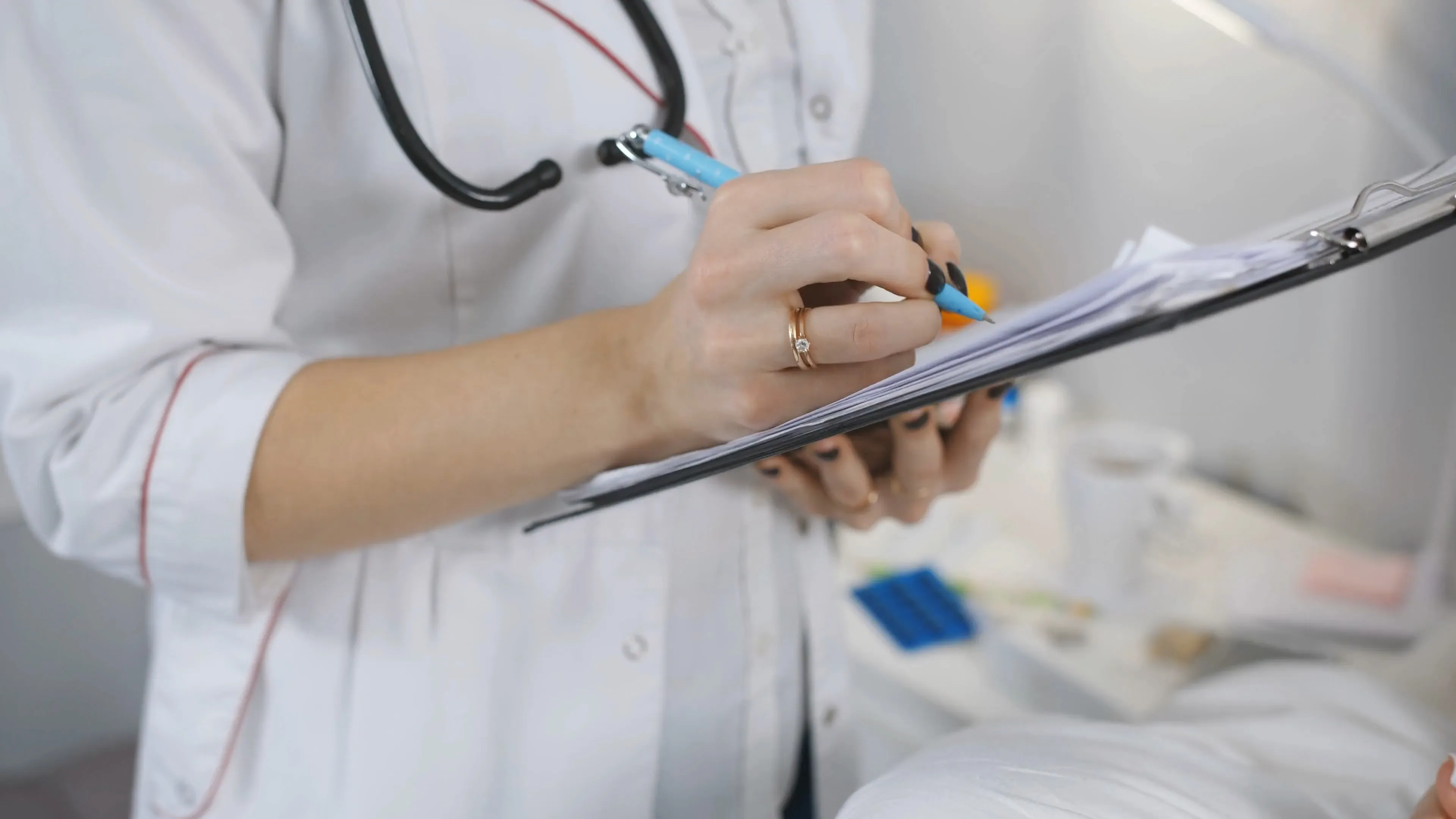 Close view of a clinician filling in a form on a clipboard by hand
